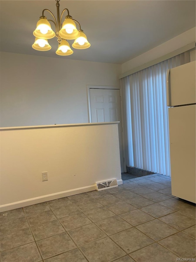 unfurnished room with visible vents, a notable chandelier, baseboards, and tile patterned floors