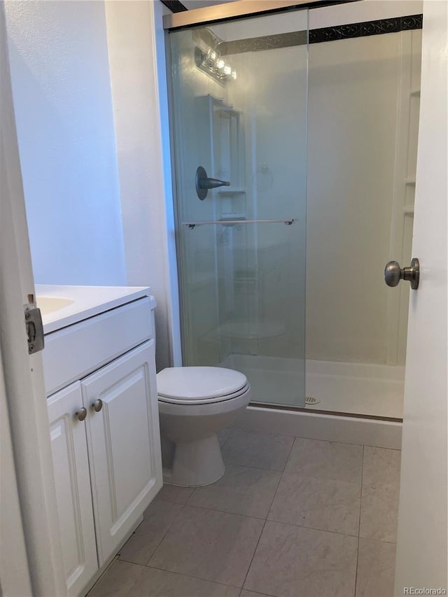 bathroom with toilet, a shower stall, vanity, and tile patterned floors