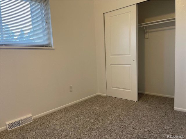 unfurnished bedroom with a closet, carpet, visible vents, and baseboards