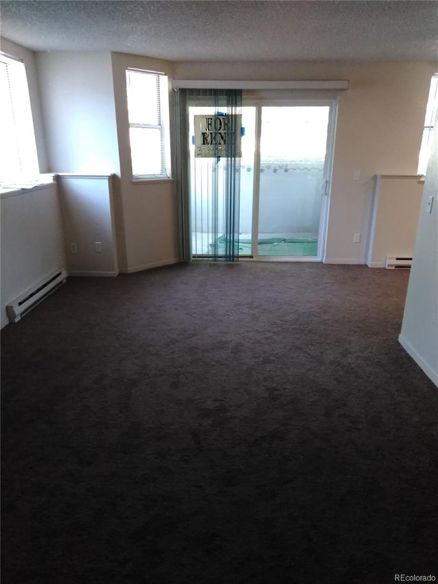 carpeted spare room featuring a baseboard heating unit and a textured ceiling