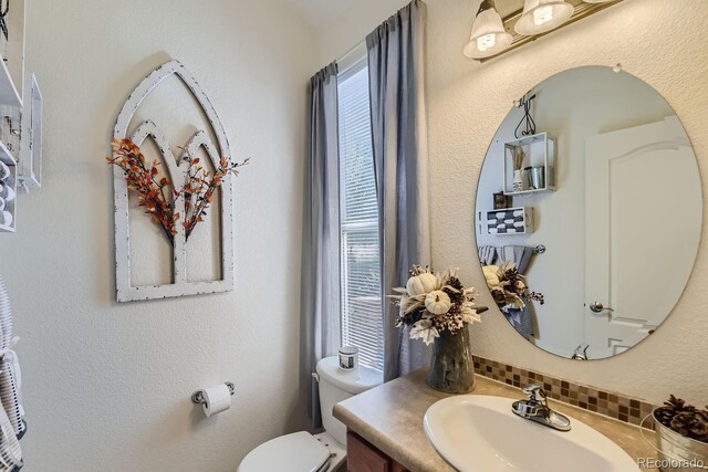 bathroom with vanity, toilet, and decorative backsplash