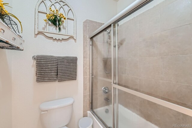 bathroom featuring shower / bath combination with glass door and toilet