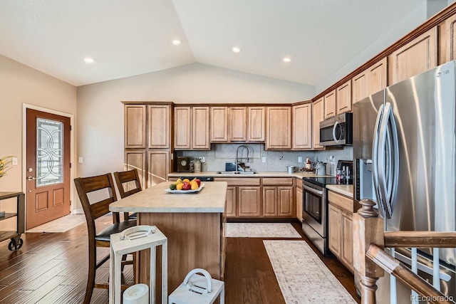 kitchen with tasteful backsplash, stainless steel appliances, hardwood / wood-style flooring, lofted ceiling, and a center island