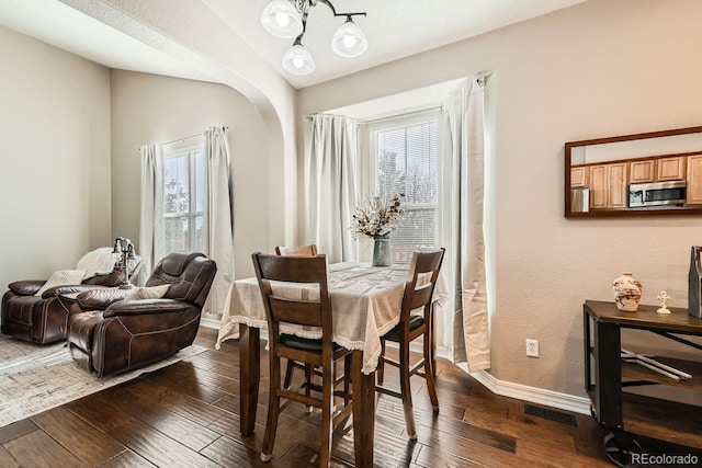 dining space featuring dark hardwood / wood-style floors, vaulted ceiling, and an inviting chandelier