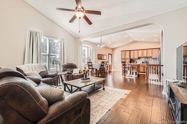 living room featuring dark wood-type flooring, ceiling fan with notable chandelier, sink, and high vaulted ceiling