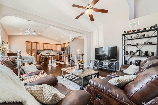 living room with ceiling fan with notable chandelier, dark wood-type flooring, and high vaulted ceiling