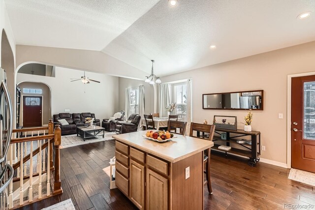 kitchen with decorative light fixtures, a breakfast bar area, dark wood-type flooring, lofted ceiling, and a center island