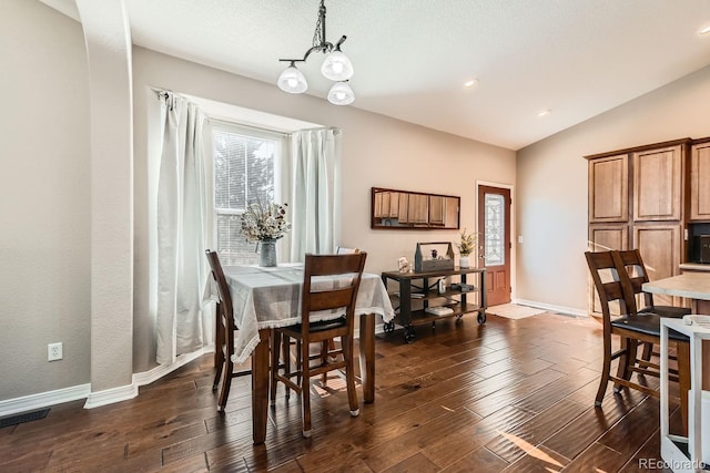 dining room with lofted ceiling, a notable chandelier, and dark hardwood / wood-style floors