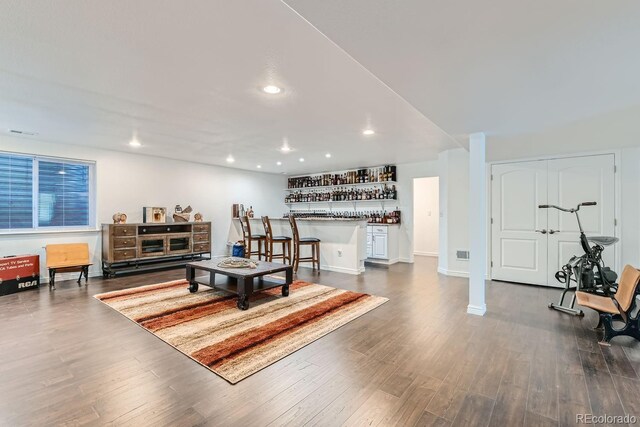 living room with dark hardwood / wood-style flooring and indoor bar