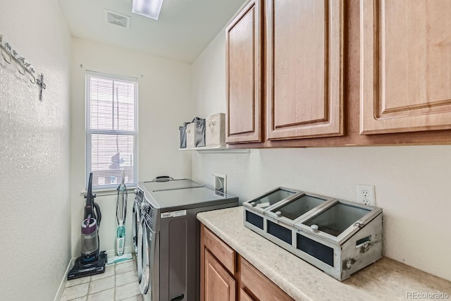 clothes washing area featuring washing machine and dryer, cabinets, and light tile patterned floors