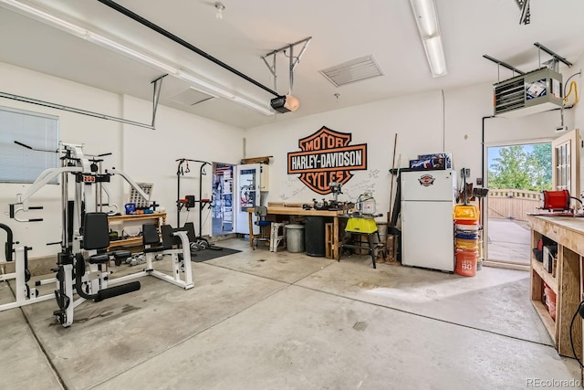 garage with a garage door opener, white refrigerator, and a workshop area