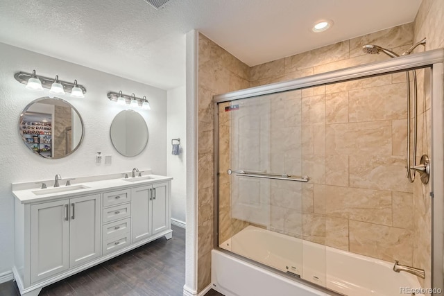 bathroom featuring hardwood / wood-style flooring, vanity, a textured ceiling, and enclosed tub / shower combo