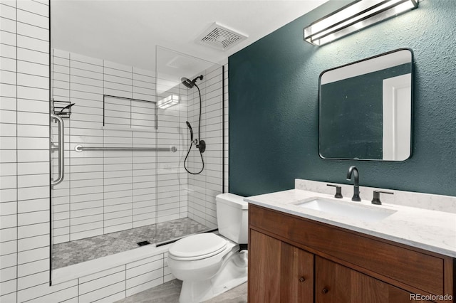 bathroom with toilet, vanity, and a tile shower