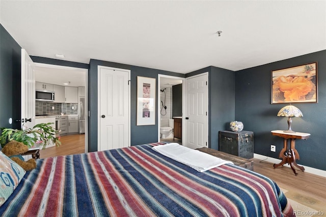 bedroom with connected bathroom and light hardwood / wood-style flooring