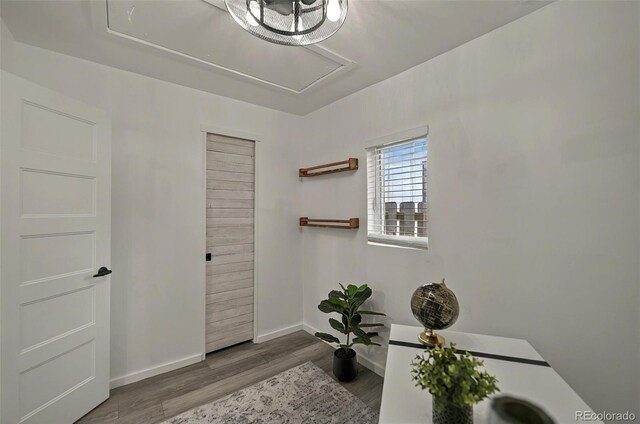 office space with wood finished floors, attic access, and baseboards