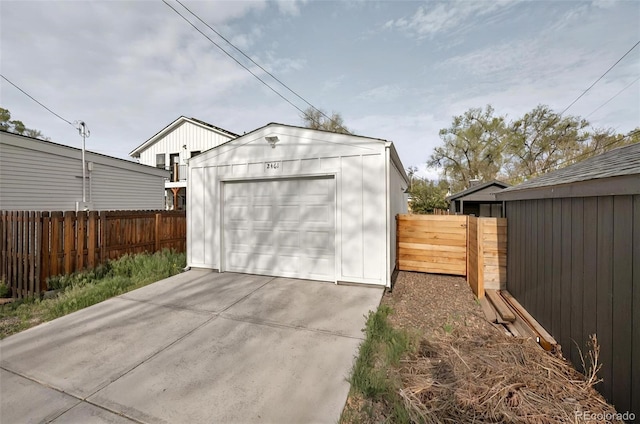 detached garage featuring fence and concrete driveway