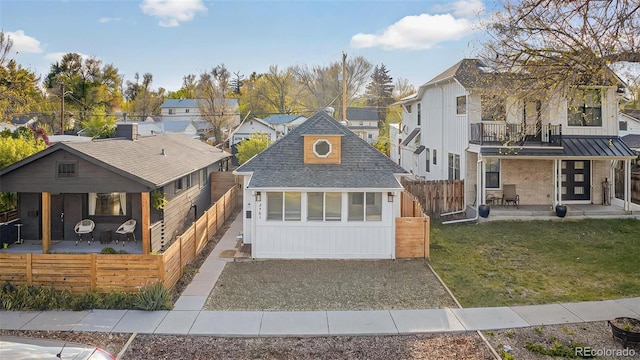 view of front of house featuring a residential view, a balcony, an outbuilding, and board and batten siding