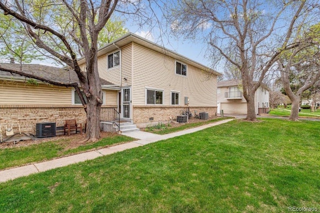 view of front of home with a front yard, brick siding, and central AC