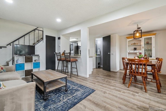 living area with stairway, wood finished floors, baseboards, a textured ceiling, and recessed lighting