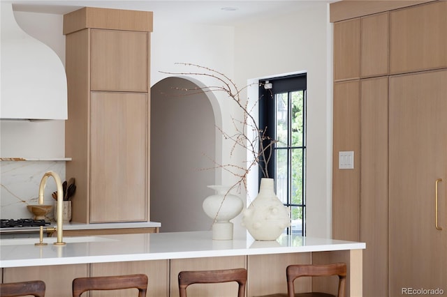 5800 E 6th Avenue Parkway, Denver, CO 80220 - detailed view of a breakfast bar, modern cabinets, light countertops, light brown cabinetry, and extractor fan