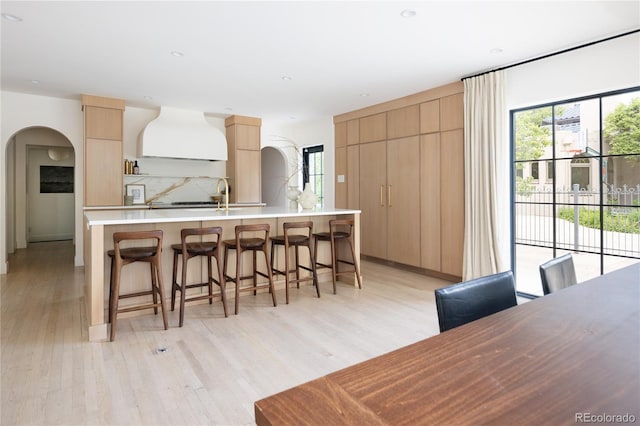 5800 E 6th Avenue Parkway, Denver, CO 80220 - kitchen with light brown cabinetry, modern cabinets, arched walkways, custom exhaust hood, and light wood finished floors