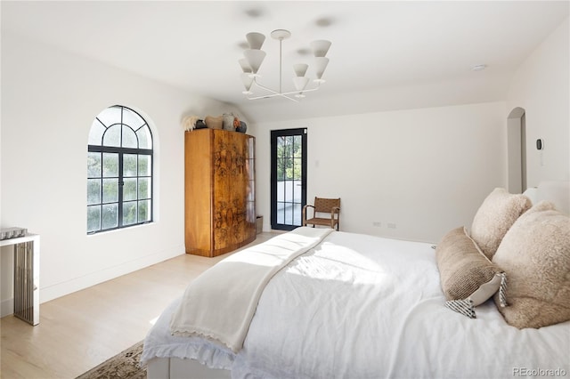5800 E 6th Avenue Parkway, Denver, CO 80220 - bedroom featuring light wood-type flooring, a chandelier, arched walkways, and access to outside