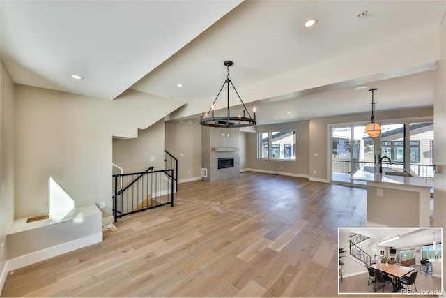 living room with light hardwood / wood-style flooring, a chandelier, and a fireplace