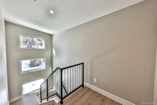 stairway with hardwood / wood-style floors and lofted ceiling