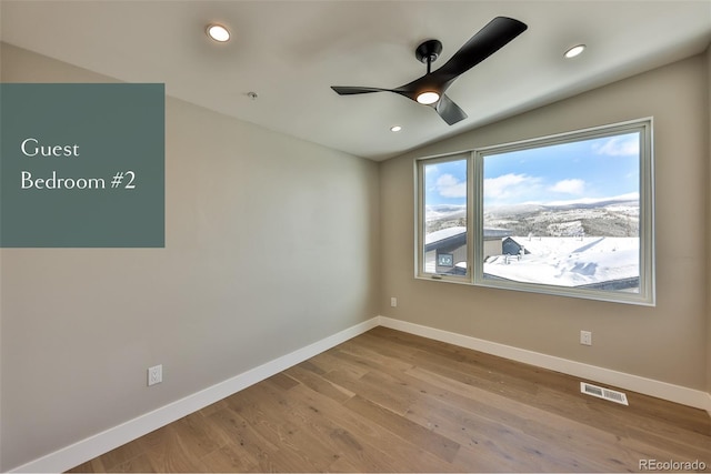 spare room featuring ceiling fan, light wood-type flooring, and lofted ceiling