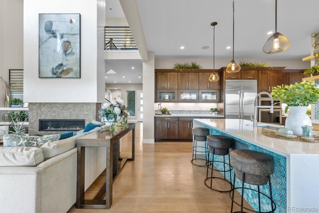 481 Meadowleaf Ln, Highlands Ranch, CO 80126 - kitchen with appliances with stainless steel finishes, light countertops, light wood-type flooring, a breakfast bar area, and hanging light fixtures