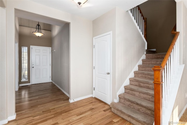 entrance foyer with light wood-type flooring, stairway, and baseboards