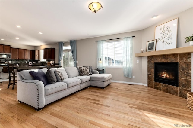 living area featuring light wood-style floors, a fireplace, baseboards, and recessed lighting