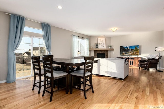 dining space with light wood-type flooring, recessed lighting, baseboards, and a tile fireplace