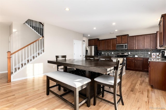 dining room with recessed lighting, light wood-style flooring, baseboards, and stairs