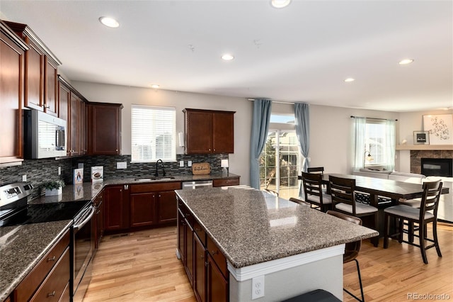 kitchen with a breakfast bar area, recessed lighting, decorative backsplash, appliances with stainless steel finishes, and light wood-style floors