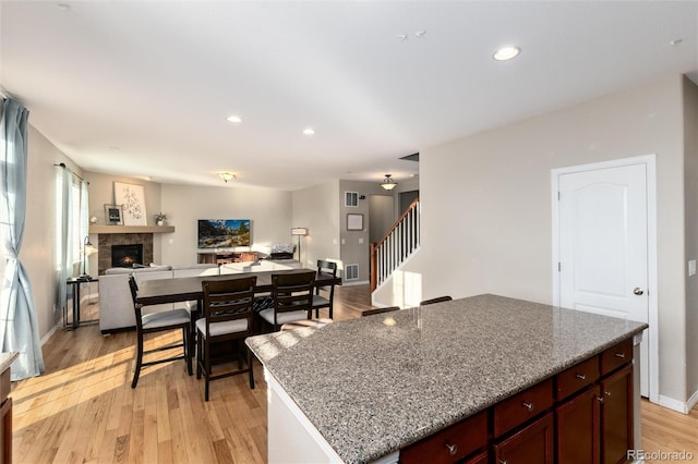 kitchen with recessed lighting, a fireplace, a kitchen island, and light wood-style floors