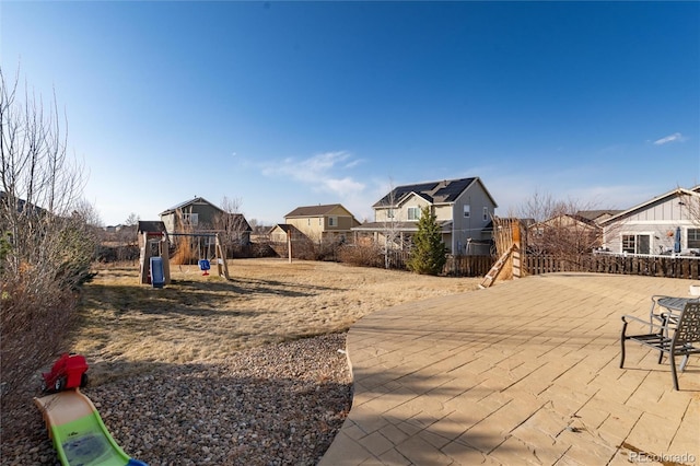 view of yard featuring a patio area, a residential view, fence, and a playground