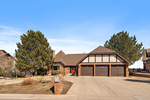 tudor home featuring driveway, a chimney, an attached garage, and stucco siding