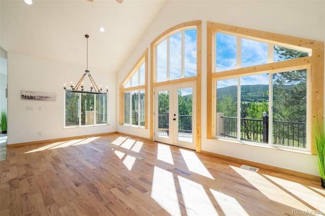 unfurnished living room with a chandelier, high vaulted ceiling, wood finished floors, baseboards, and recessed lighting