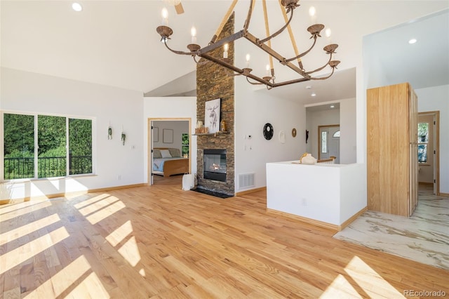 unfurnished living room with high vaulted ceiling, a chandelier, a stone fireplace, baseboards, and recessed lighting