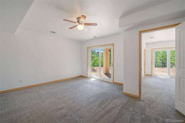 carpeted spare room featuring a ceiling fan and baseboards