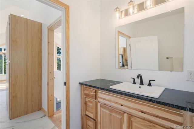 bathroom featuring marble look tiles, vanity, and healthy amount of natural light
