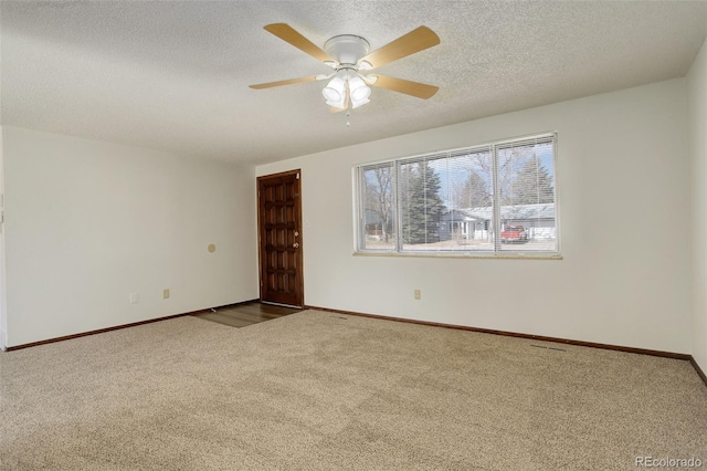 carpeted spare room featuring a ceiling fan, a textured ceiling, and baseboards