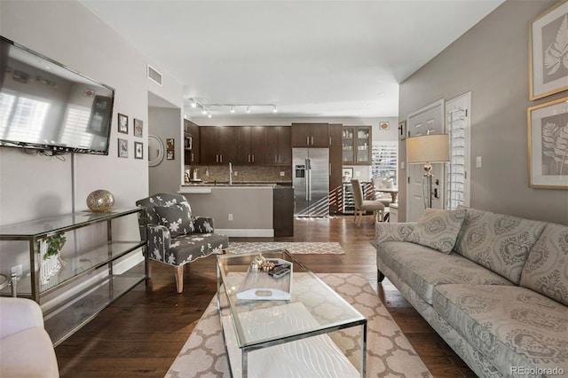 living room featuring dark wood-type flooring, track lighting, and sink