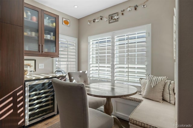 dining room featuring wood-type flooring, beverage cooler, and indoor bar