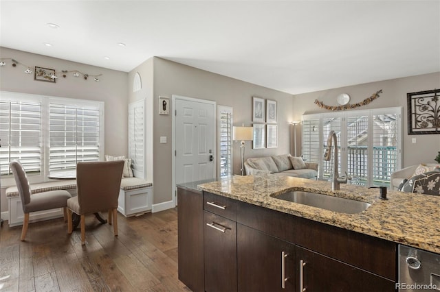 kitchen featuring sink, dark hardwood / wood-style flooring, light stone counters, dark brown cabinetry, and a healthy amount of sunlight