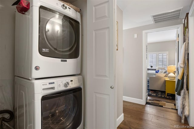 clothes washing area featuring stacked washer / drying machine and dark hardwood / wood-style floors