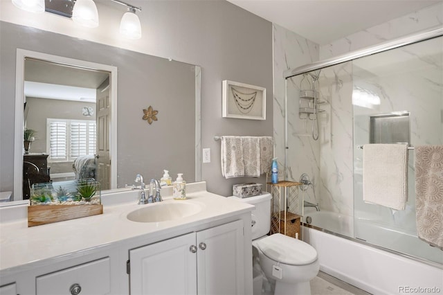 full bathroom featuring vanity, combined bath / shower with glass door, and toilet