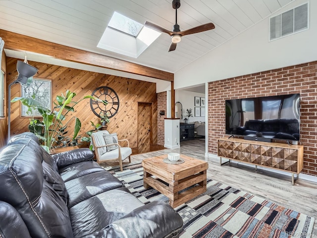 living room featuring wood walls, lofted ceiling with skylight, wood finished floors, and visible vents