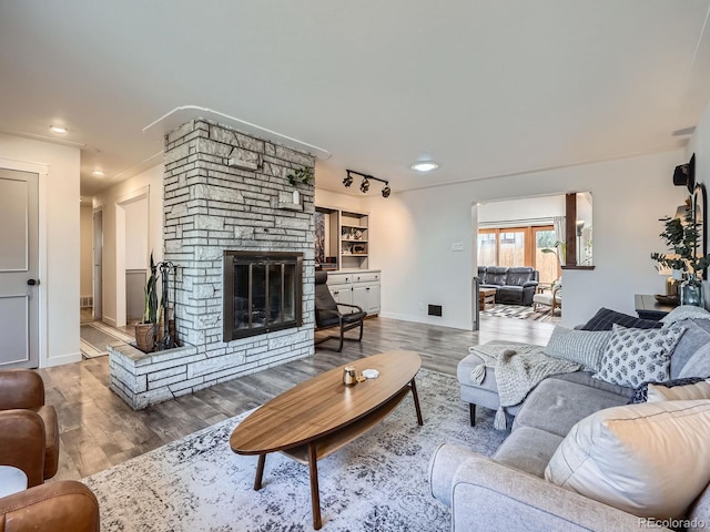 living room with a fireplace, baseboards, track lighting, and wood finished floors